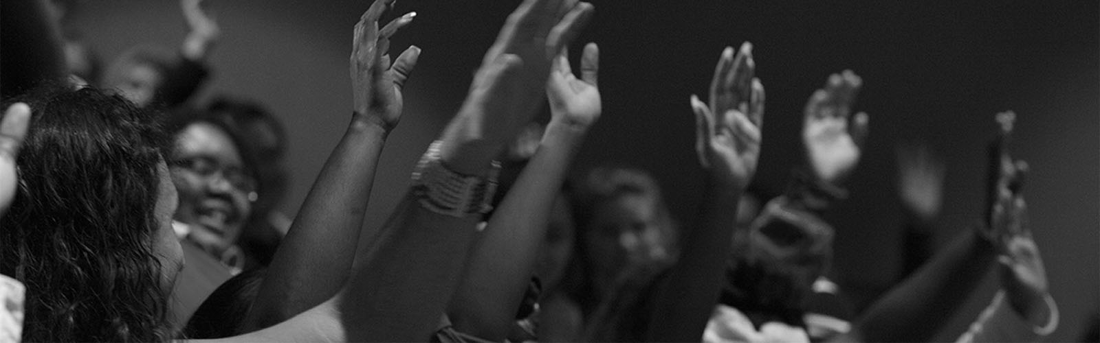 Image of a group of people with hands raised.