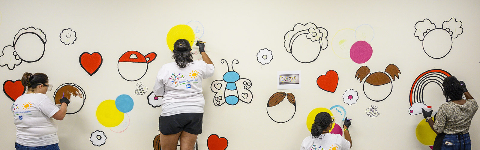 From left to right, Kim Blair, senior director of development at the UW Foundation; Desiree Bates, co-lead on the UW Bridge to the Chemistry Doctorate Program, and UW computational chemist; Shannon Brown, UW graduate student and Bridge Fellow; and Candace Patterson, South Madison Partnership coordinator work on a mural on the wall of the Kids Classroom designed by Madison-based artist Lilada Gee at the UW South Madison Partnership on South Park Street in Madison, Wisconsin on Aug. 18, 2022. The mural painting project was developed in collaboration with UW South Madison Partnership staff, the paint company PPG’s Colorful Communities program, and campus partners. The murals reflect Gee’s bold and colorful style and are designed to inspire the community and families that use the location for programming. (Photo by Althea Dotzour / UW–Madison)